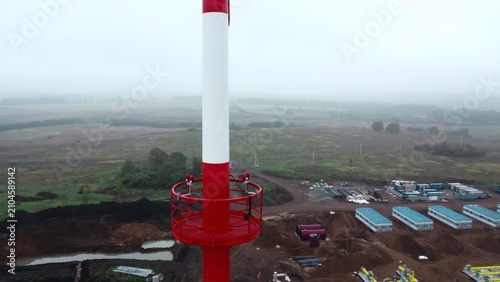 Fotografía Red and white industrial tower above a foggy rural landscape