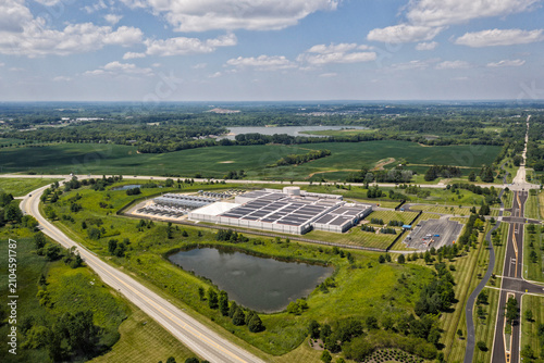 Aerial view of the data center complex, large AI center structure surrounded by pond and green countryside areas 