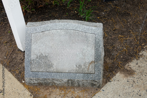 Blank granite gravestone or marker on the ground by a sidewalk