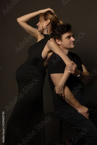 фотографія A pregnant slim girl poses with her husband in black outfits
