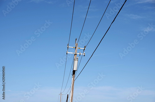 Simple rural electricity distribution pylon and power lines under blue sky