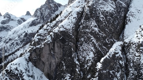 Snow-covered rocky mountain cliffs with evergreen trees in a cold alpine winter landscape . Media