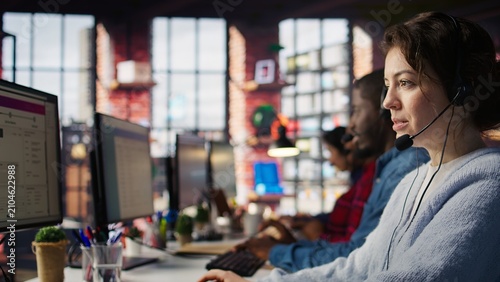 Canvas Print A call center agent handles inbound calls and customer inquiries, updates account records and works toward performance metrics in a close-up workplace scene during a busy office workday