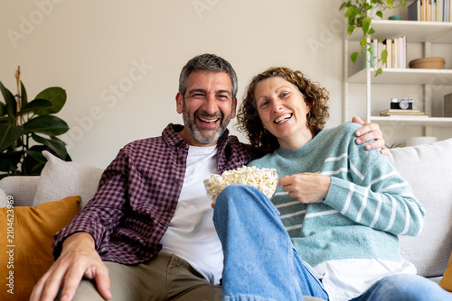 Happy couple enjoying leisure time eating popcorn at home