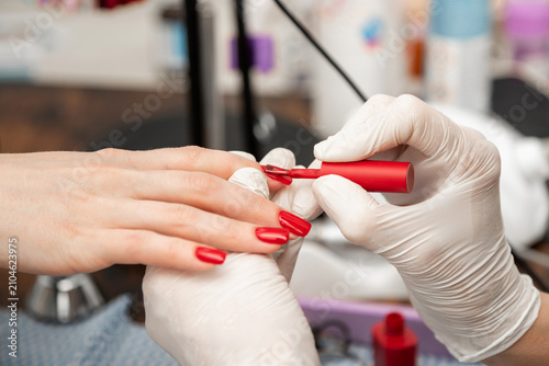 Professional Nail Technician Applying Red Nail Polish to Client