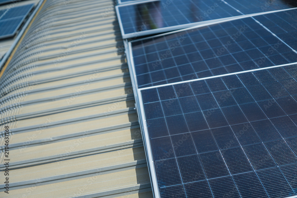 Fototapeta premium The completed solar array turns the old factory roof into a shining power plant, orderly on the sweeping metal roof of a manufacturing plant in Southeast Asia, during the fit out.