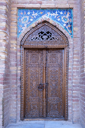 Ornate Carved Wooden Door with Islamic Tilework in Uzbekistan