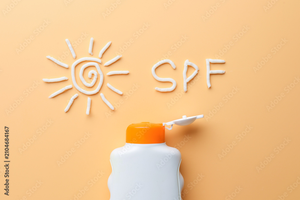 Obraz premium Sun made of sunscreen, abbreviation SPF and bottle of sun protection cream on beige background, top view