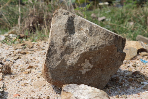 Single weathered rock placed on dusty ground during excavation and landscape preparation activities