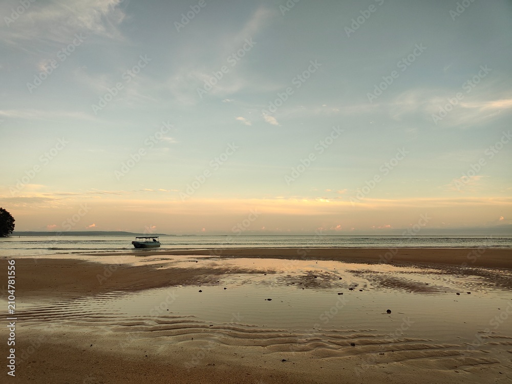 Obraz premium Low Tide Beach with Traditional Boat at Ora Beach, Maluku, Indonesia