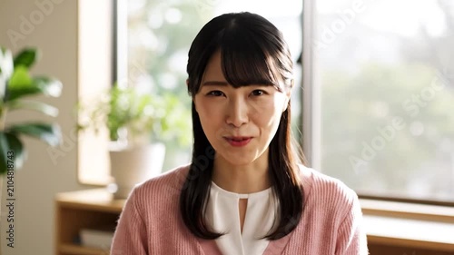 A smiling young woman looks directly at the camera indoors