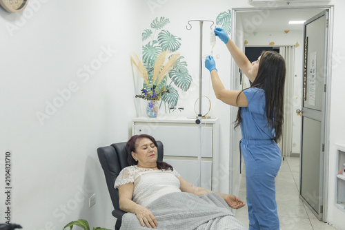 Εκτύπωση καμβά Healthcare professional adjusting an intravenous drip bag while an elderly patient receives infusion therapy in a modern outpatient medical clinic