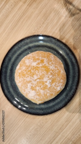 Top view of artisanal baked bread served on a black ceramic plate over a rustic wooden table background