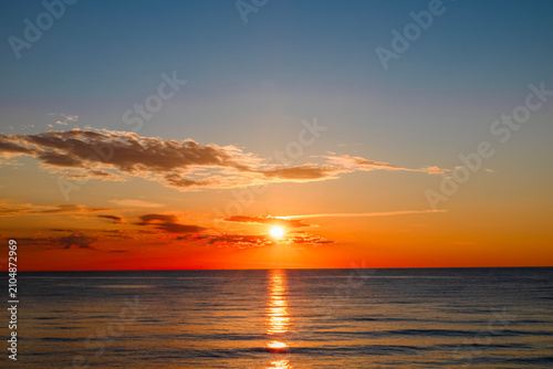 seascape: setting sun in clouds, reflected in the water