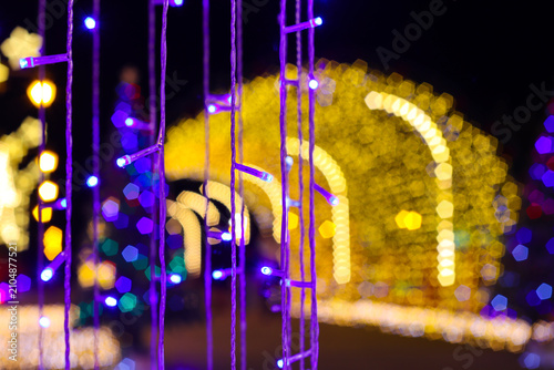 Purple LED light curtain in foreground with golden yellow tunnel bokeh background. Winter illumination festival night scene decoration