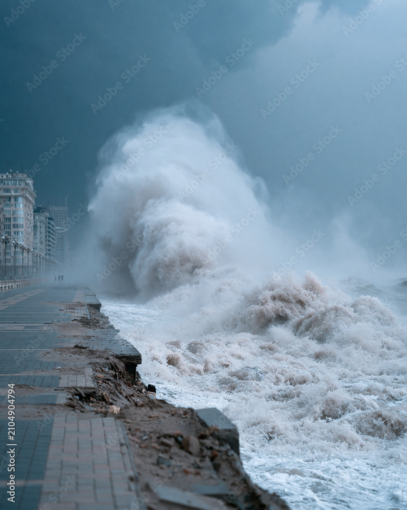 Fototapeta premium Stormy sea crashes against broken coastal walkway. Foam explodes under dark, threatening skies. Broken tiles and rubble mark erosion's fury. Distant buildings stand silent, battered by wind