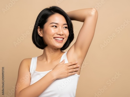 Smiling asian woman showing smooth underarm with she is wearing a white tank top white background