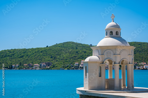 Photos White stone baptistry Suza Njegoseva Tivat Montenegro by blue sea with green hills background, serene coastal landmark view