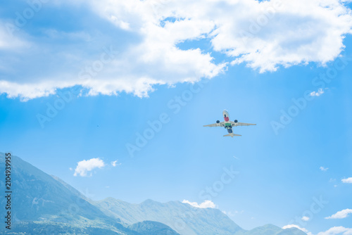 Foto Airplane flying through clear blue sky with fluffy white clouds and distant mountains, scenic travel adventure aviation view