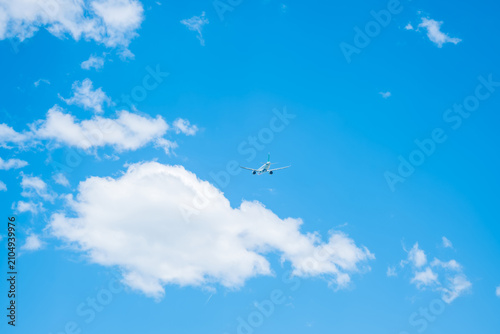 Foto A small airplane flying in a clear blue sky with fluffy white clouds
