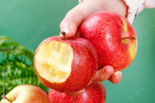 Hand Holding Fresh Red Apples with One Bitten Apple