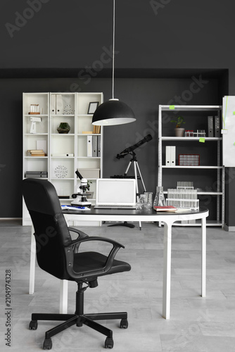 Interior of laboratory with workplace, shelf units and telescope