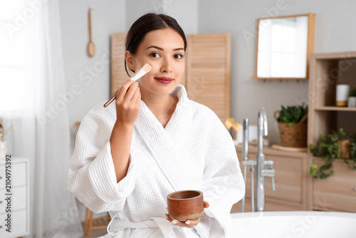 Young woman applying facial...