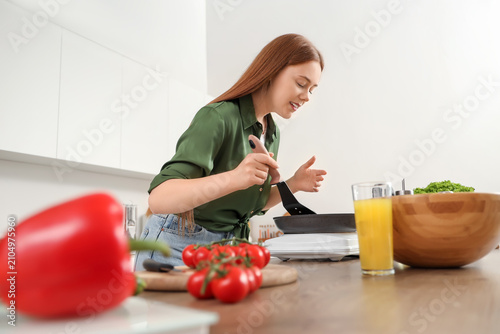 Young woman frying vegetabl...