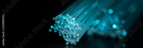Macro view of glowing blue fiber optic cable strands with technology communication internet transmission electronic connectivity bandwidth connection infrastructure
