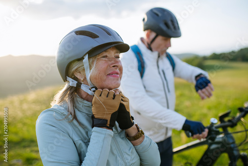 Obraz na plátne Older bikers taking break during bike ride and checking their performance on smartwatch