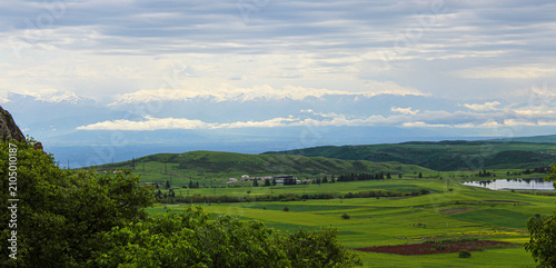 Tableau sur toile Green, plowed fields among hills covered with grass and shrubs