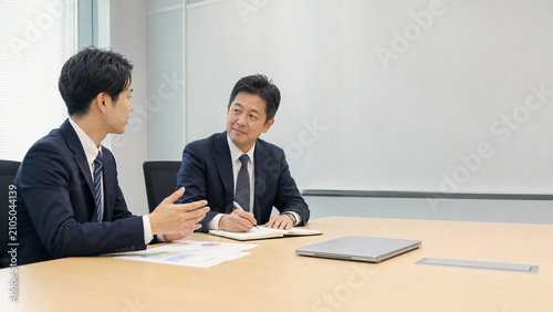 Senior manager consulting with younger employee during office meeting