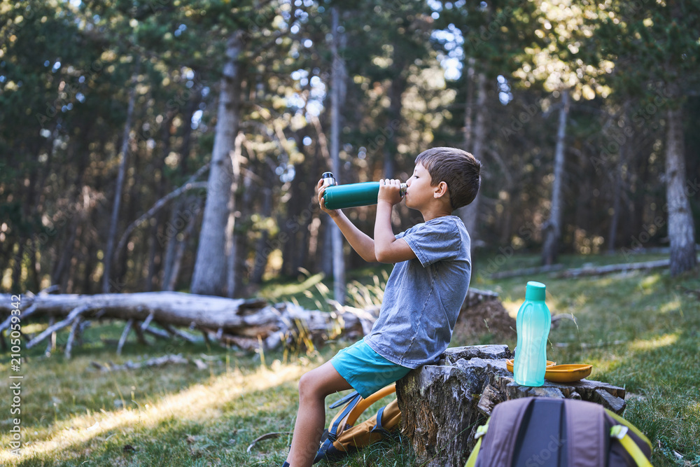 Fototapeta premium Boy drinking water during a forest hiking break