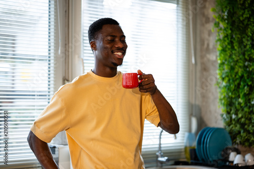 Quadro su tela Young black man enjoying morning coffee in kitchen