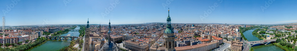 Obraz premium Panoramic aerial cityscape view of Zaragoza and Ebro river from top of the Basilica of Our Lady of the Pillar, wide angle cityscape of historic city center, bridges and river bend in Aragon, Spain.