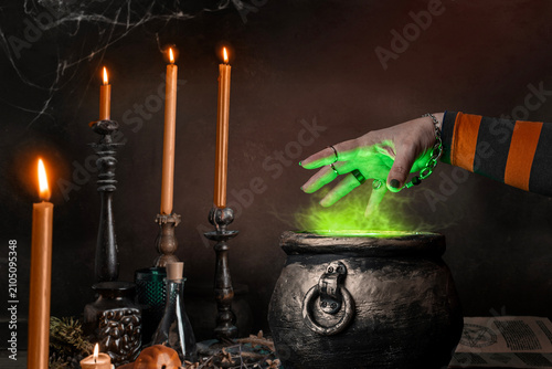 Fotografie Witch's hand over a cauldron with a magic potion in a dark room