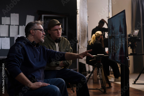 Director and crew member review video playback on a studio monitor