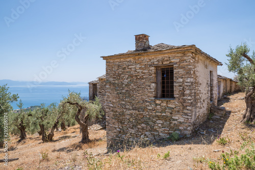 Foto Old abandoned stone houses in a farm of olive trees overlooking the Pagasetic se