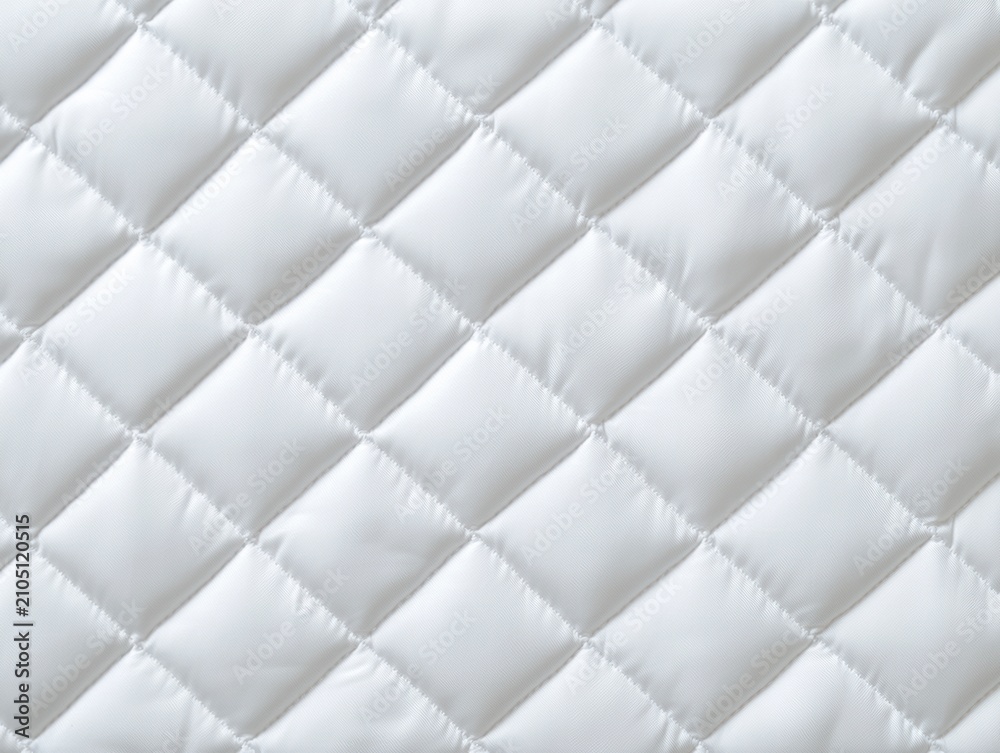 Obraz premium White quilted fabric with a diamond stitch pattern, showing soft texture and subtle shadows.