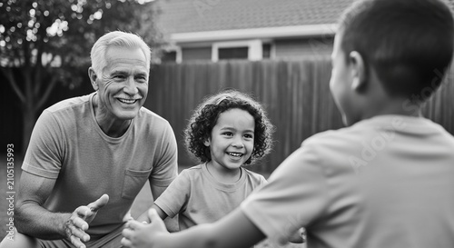 Joyful grandfather shares a happy moment with his grandchildren outdoors in black and white
