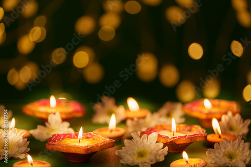 Lit clay diyas and white flowers with golden bokeh lights for Diwali