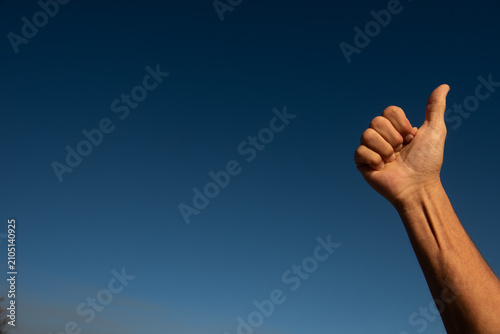 Cuadro en lienzo Hand showing thumbs up gesture against blue sky
