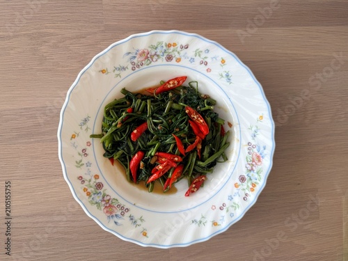 Foto Stir-fried morning glory or Pak Boong Fai Daeng on a rustic wooden table