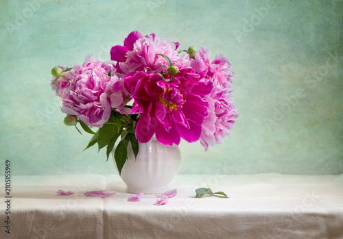Still life with a bouquet of pink peonies in a white vase on a light background