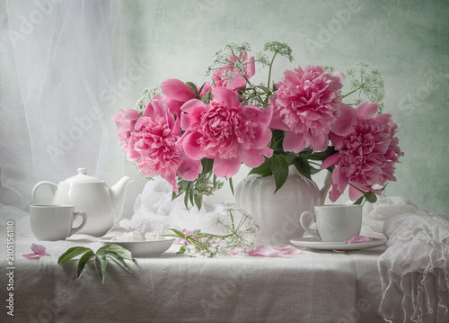 Still life with a bouquet of pink peonies in a white vase on a light background
