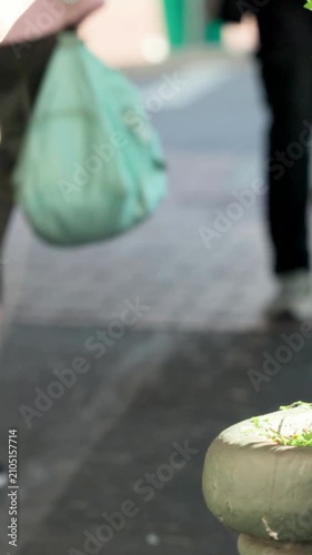 Vertical video: Entering lady in pink with mint bag walking via arcade to bright exit, copy space