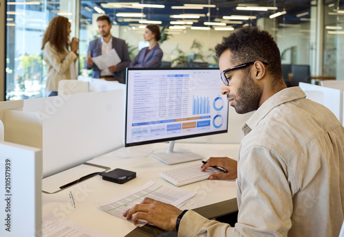 Analyst manager businessman reviewing spreadsheet charts on computer. The professional in a modern office reviews financial analytics and daily reporting. Clear concept of finance analytics.