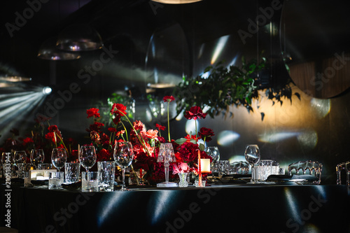 Photography Elegant banquet table with a black tablecloth and vibrant red floral centerpiece