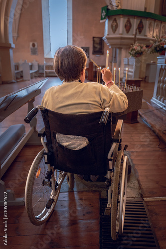 Konstfotografi Wheelchair user lighting a candle inside a historic Lutheran church