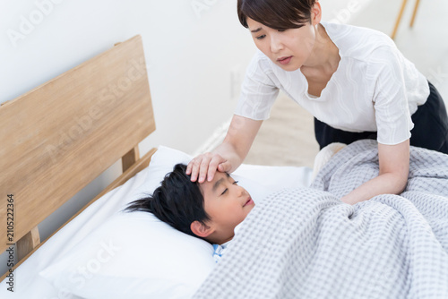 熱の子供を看病する母親